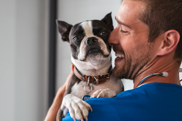 man in blue shirt smiling holding a dog